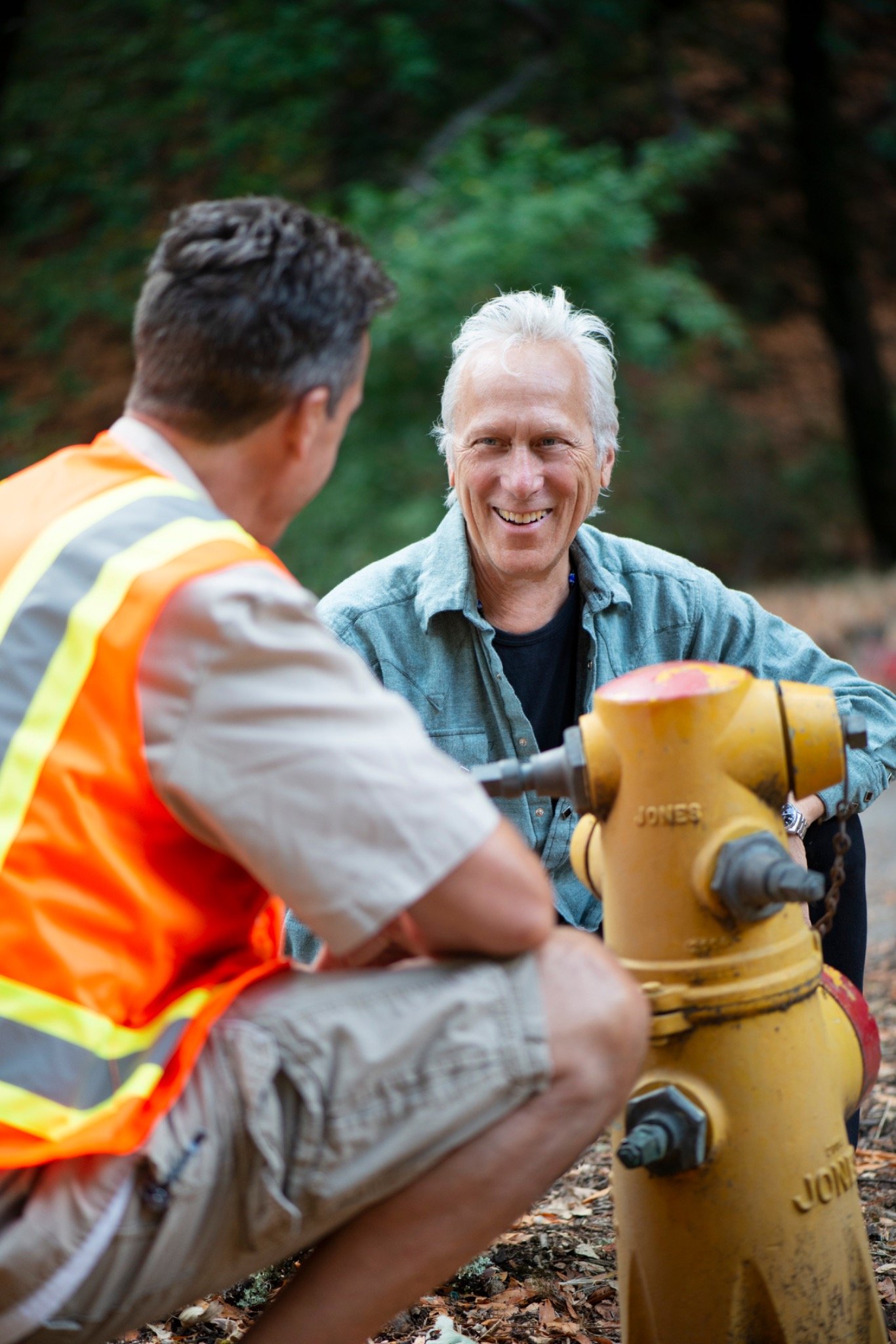 Larry Bragman speaking with a worker beside a fire hydrant